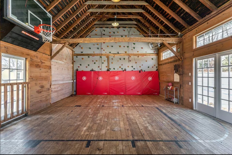 Inside the barn: basketball hoop, climbing wall, and a wide plank floor