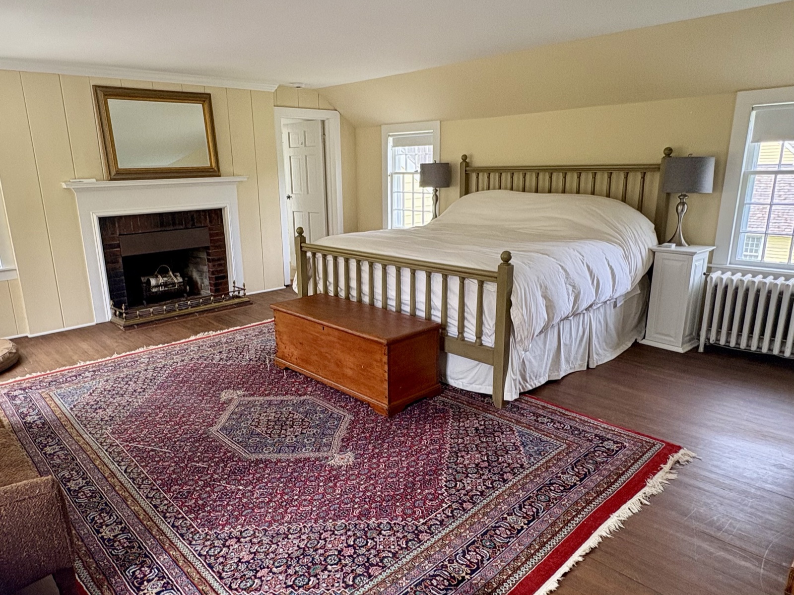 The king bedroom, fireplace laid, morning light across the floorboards