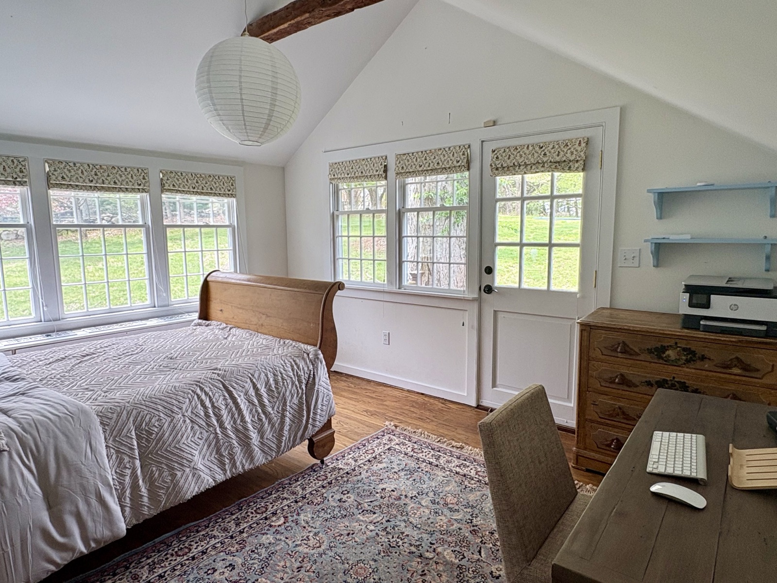A bedroom under hand-hewn beams, sleigh bed made up in white
