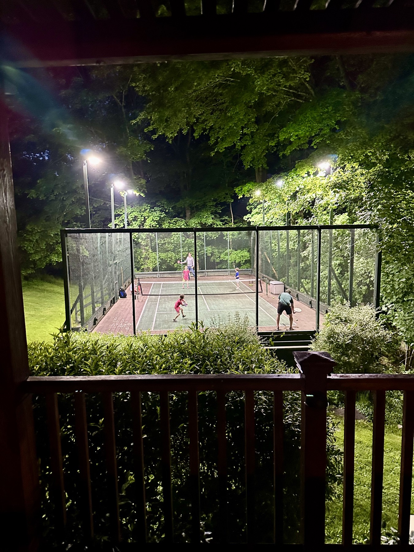 A doubles match underway on the lit platform tennis court at night