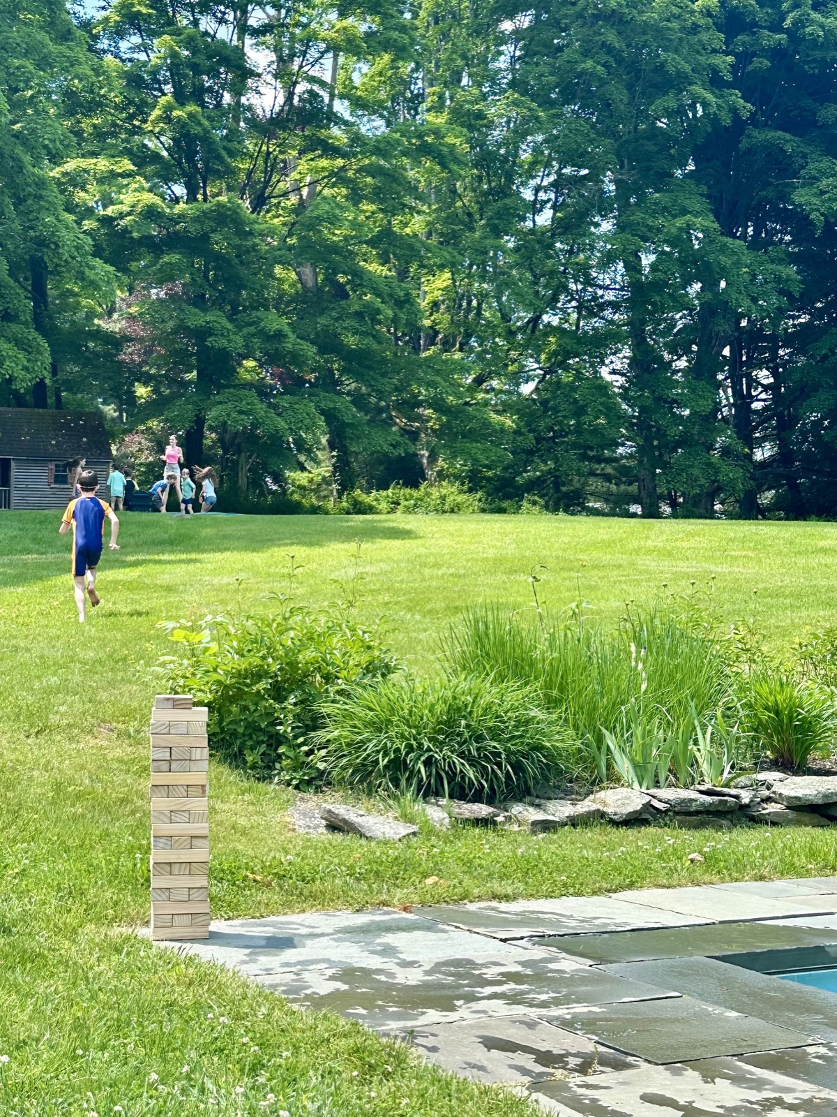 Kids running up the lawn from the pool on a summer afternoon