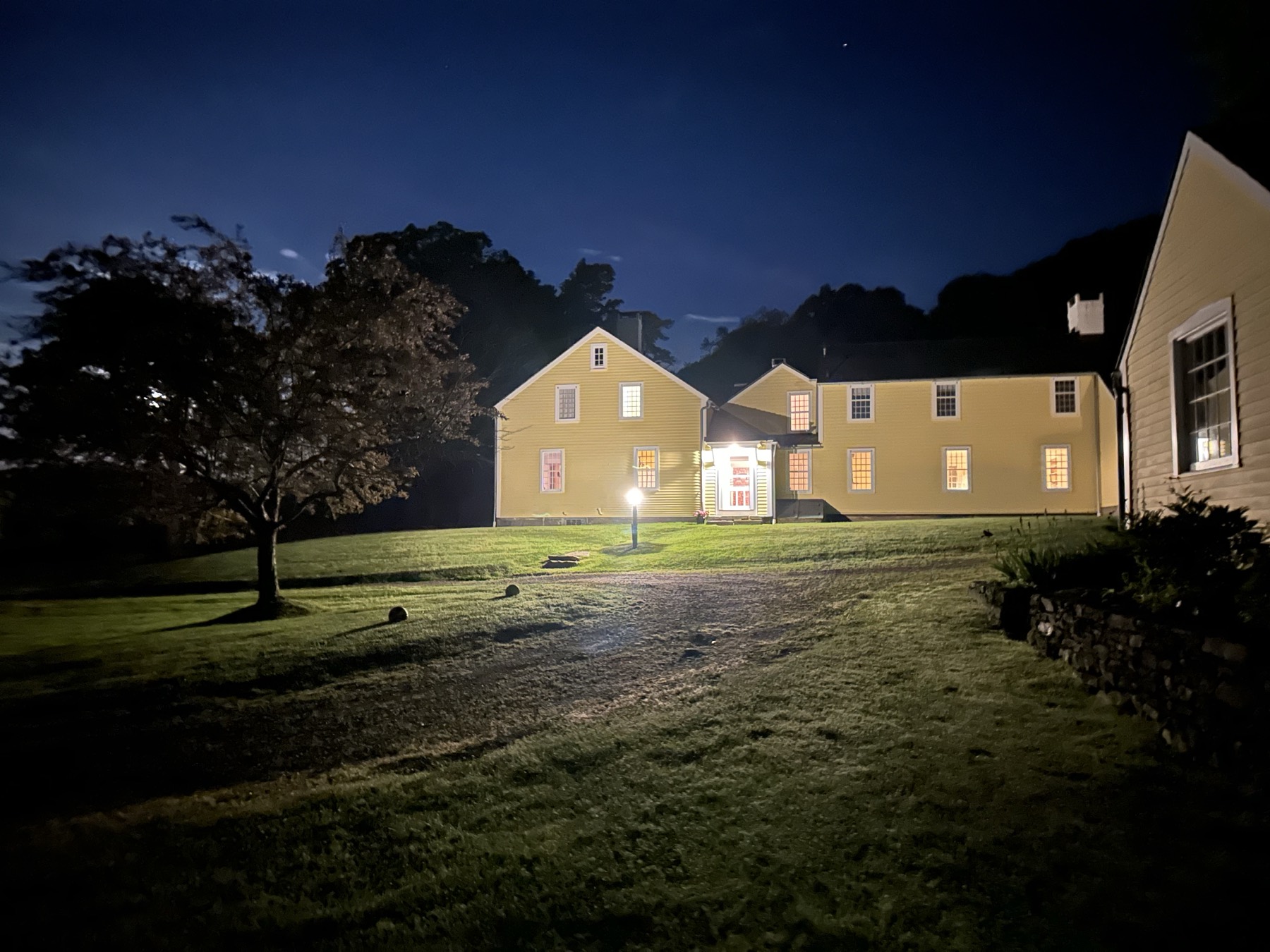 The farmhouse at night, windows lit