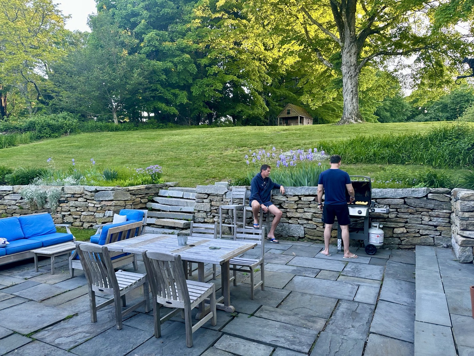 The stone patio, long table, and lawn beyond