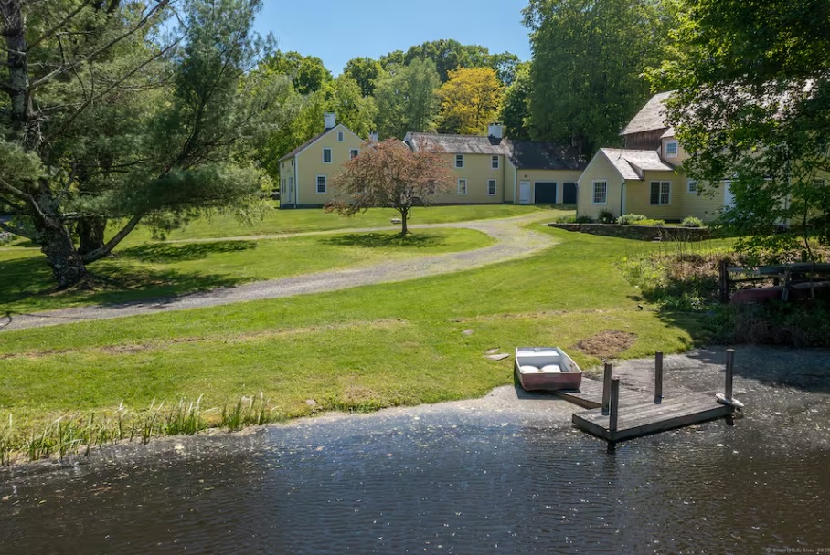 A rowboat drawn up beside the pond dock, the houses beyond