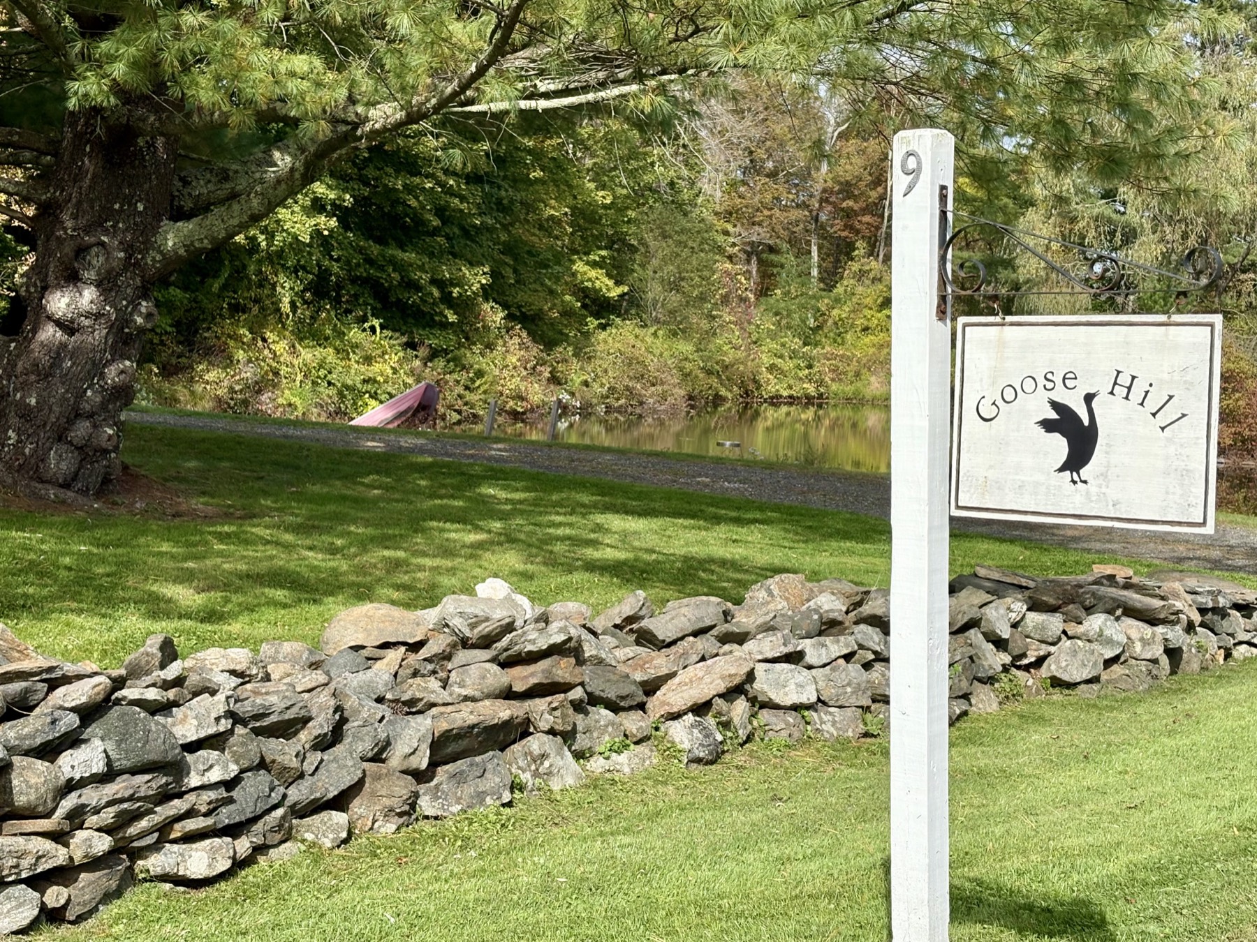 The Goose Hill sign at the stone wall, pond beyond